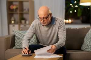 Senior man in living room with papers and a calculator