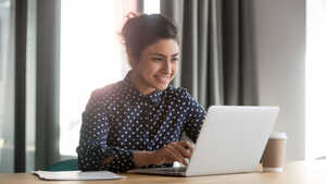 Young business woman sitting at a desk with laptop and a coffee