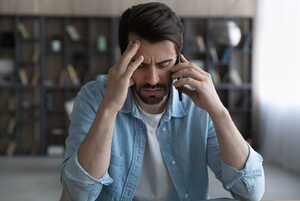 Stressed young male employee on the phone