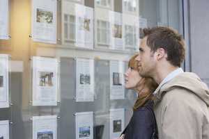 Young couple browsing estate agent's window display