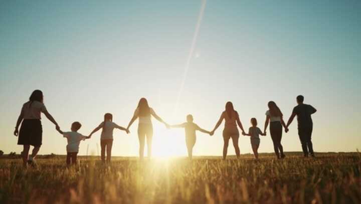 Nine children and adults holding hands and walking towards the sunset