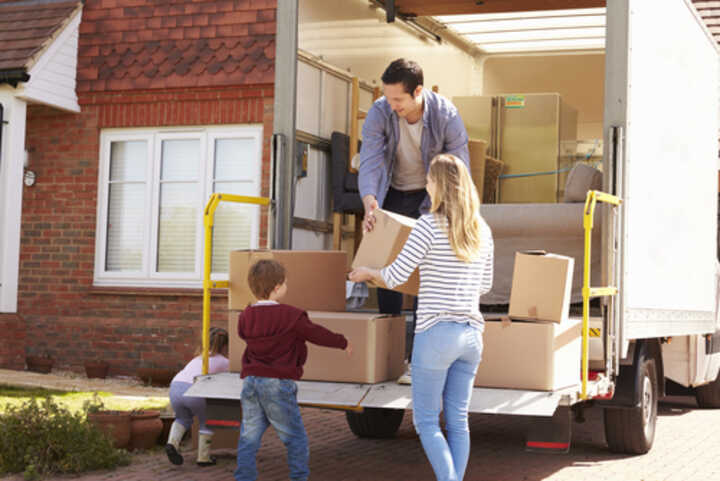 Family with young children unloading boxes from a van at their new home