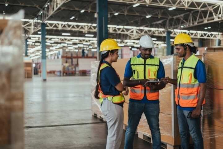 A group of three warehouse workers checking stock levels