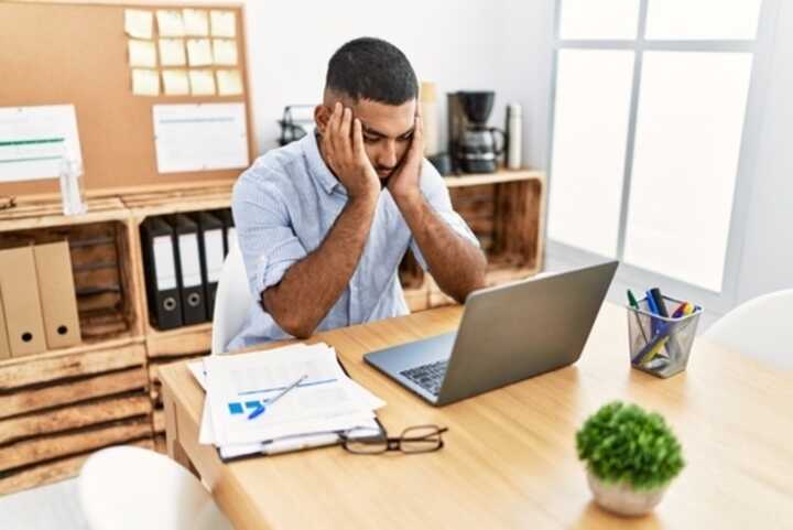 Young male employee feeling under stress as he looks at his laptop